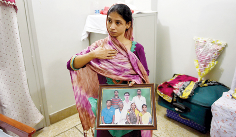 Geeta smiling and holding a framed photograph